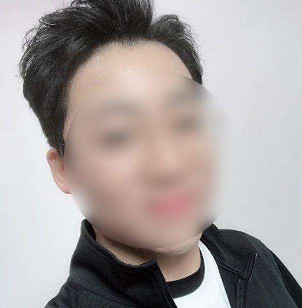 黒い服を着た人物が写っている写真です。背景は白い壁となっています。