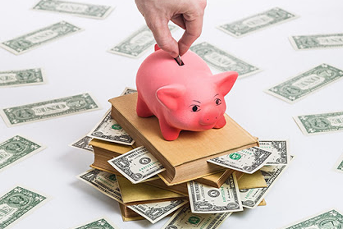 粉色存钱罐和美元纸币散落在书本上，体现了关于存款和理财的主题。