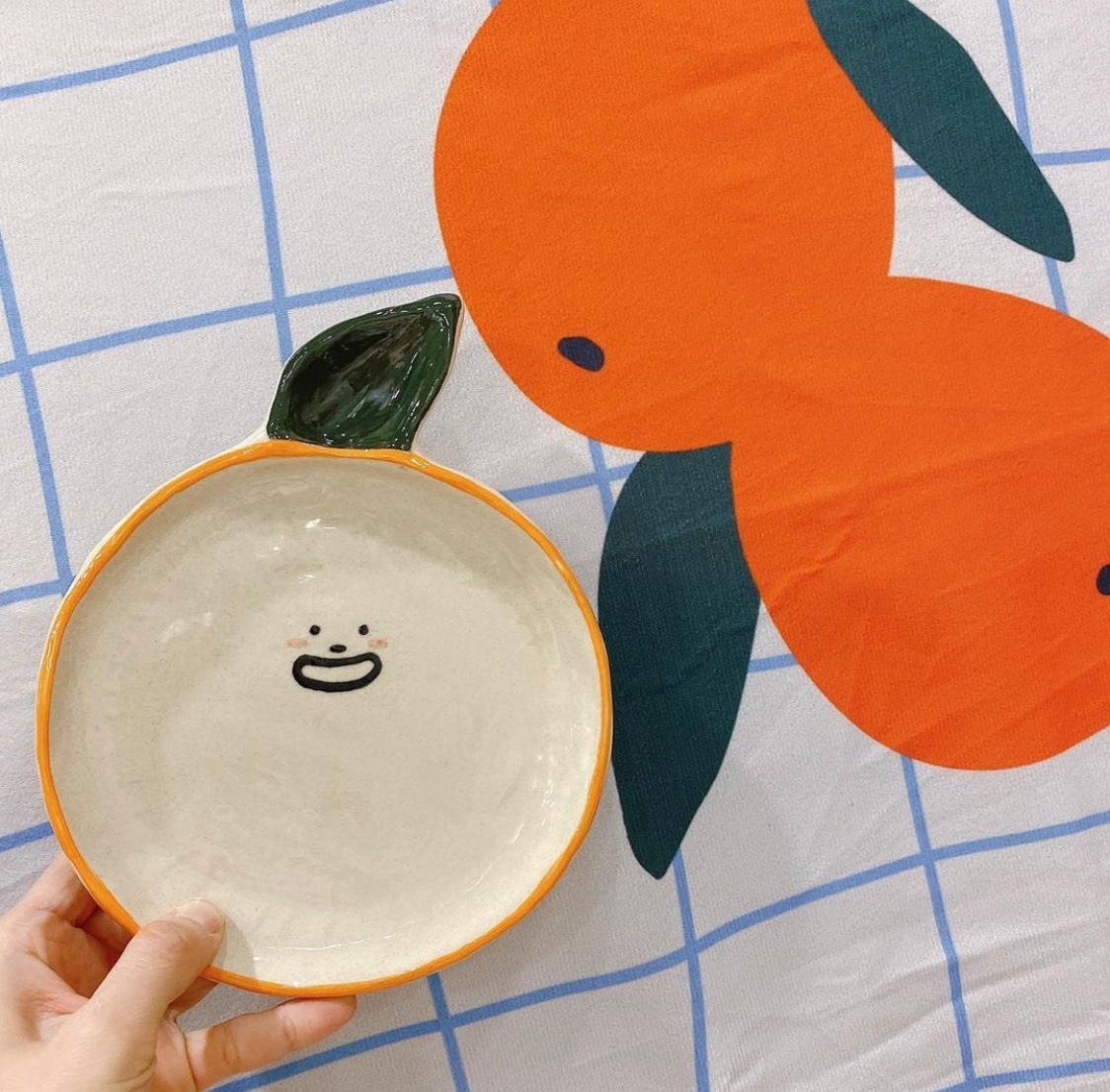 オレンジのキャラクターが描かれた韓国製陶芸品のお皿
