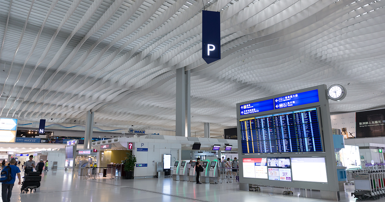 香港機場內部，展示航班信息的電子顯示屏，旅客辦理登機手續