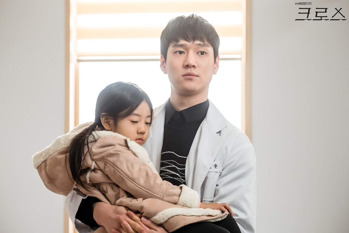 一名白袍醫生抱著一名小女孩，背景是温馨的病房環境。