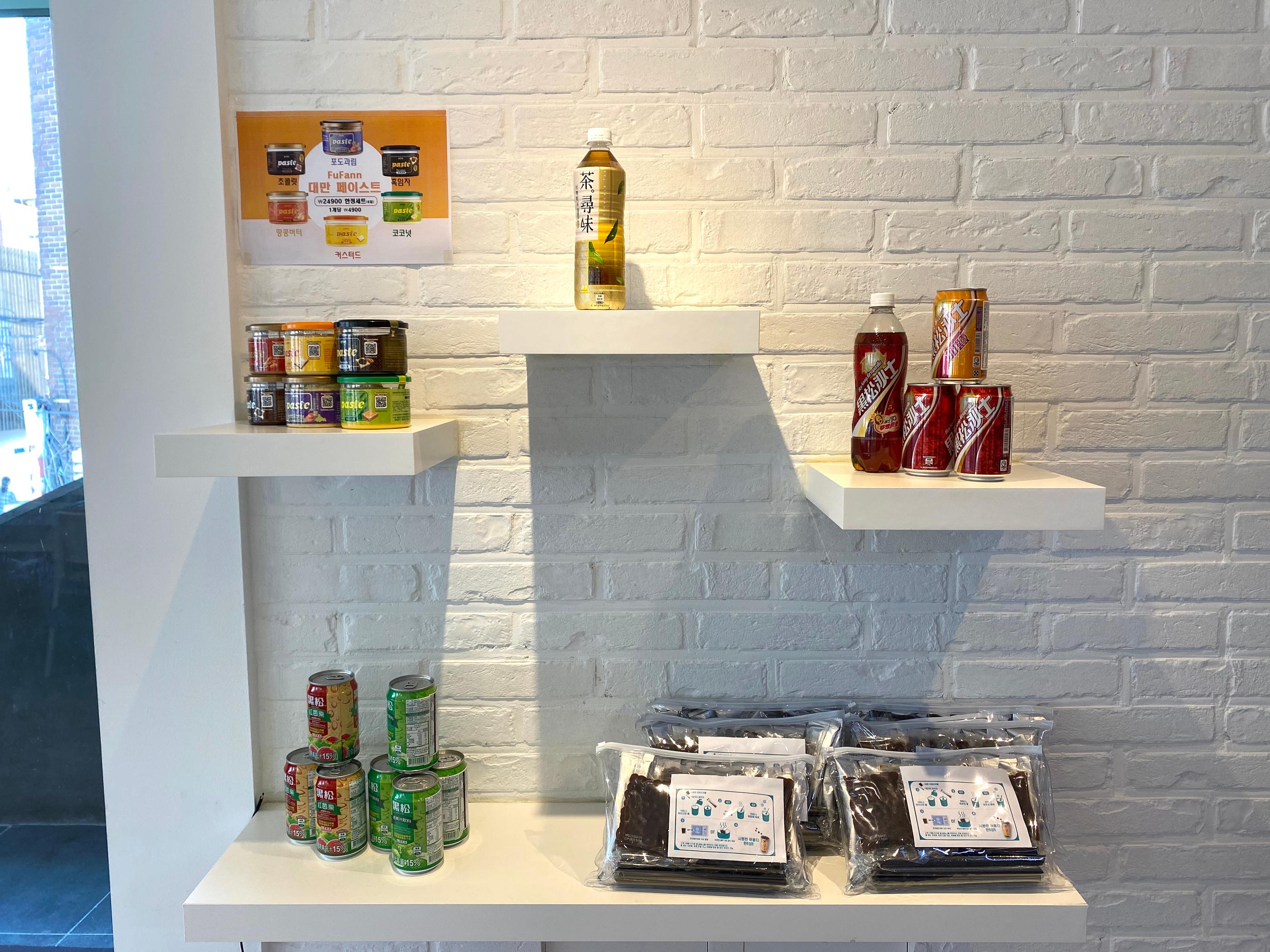 店內陳列的臺灣名產，包含飲料和特色產品，展現在簡約的白色牆面櫃檯。