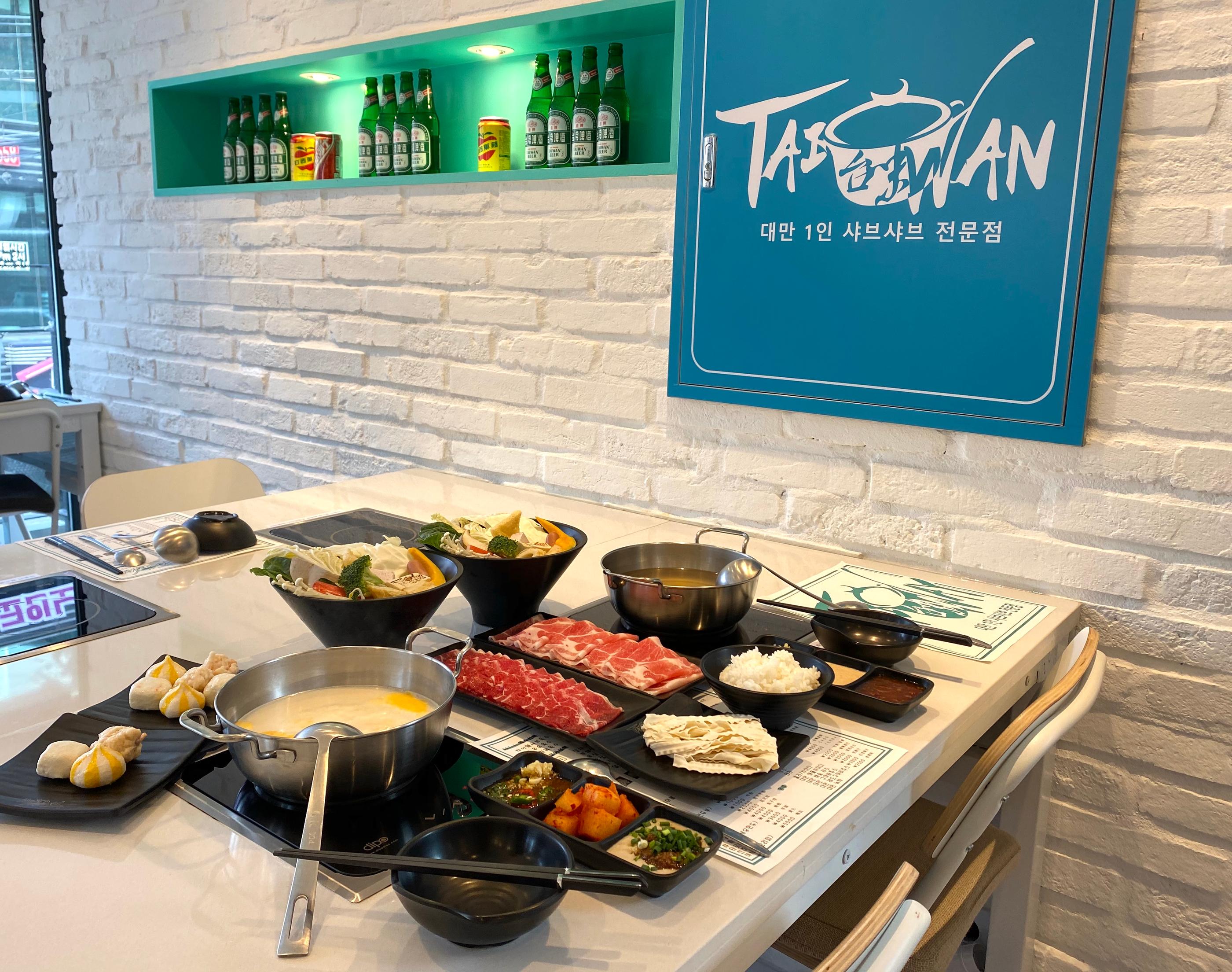 臺灣火鍋店的三國式火鍋盛滿燙白的湯底，搭配色彩豐富的食材和醬料。