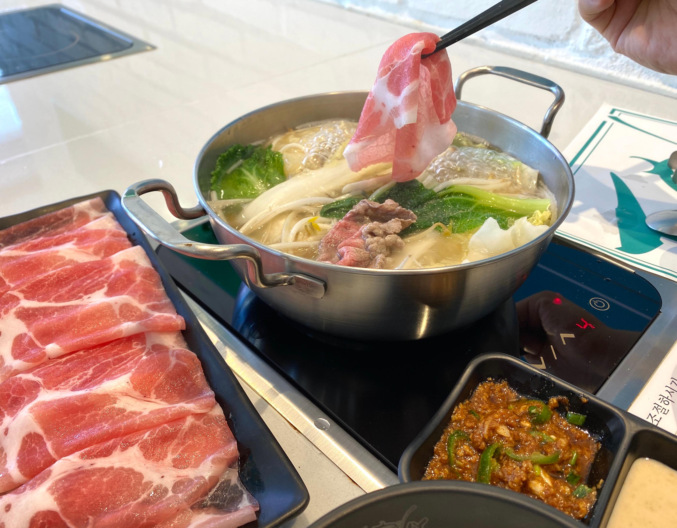 正在火鍋中烹調的彩色丸子，裡面夾滿美味的魚卵內餡，熱騰騰的畫面。