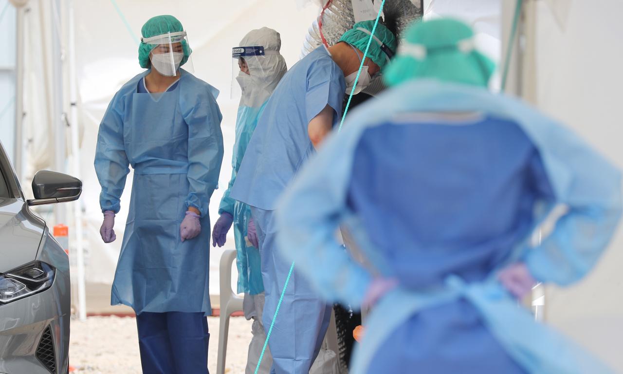 ภาพของเจ้าหน้าที่ทางการแพทย์สวมชุดป้องกันในสถานที่ตรวจเชื้อโควิด-19 ที่ศูนย์ตรวจเชื้อขับรถ ช่วงการระบาดของโควิด-19 ที่เกาหลีใต้