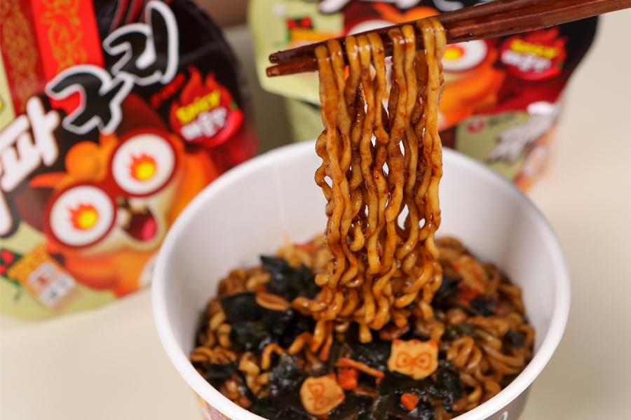Mì tương đen xoắn Nongshim với các miếng nguyên liệu phong phú, trên nền gói mì jjapa guri hấp dẫn và bắt mắt, dịch vụ quảng cáo sáng tạo.