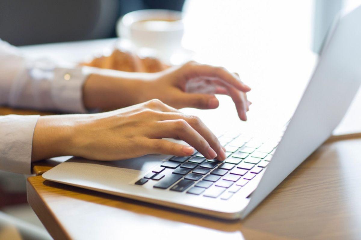 Người đang gõ bàn phím laptop.