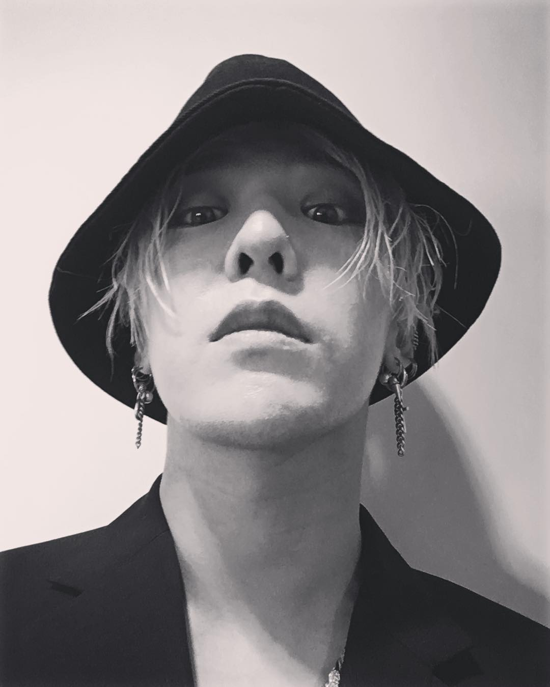 韓國著名藝人G-Dragon穿著略微軍式綠色外套，展現出他一貫的時尚和獨特風格。