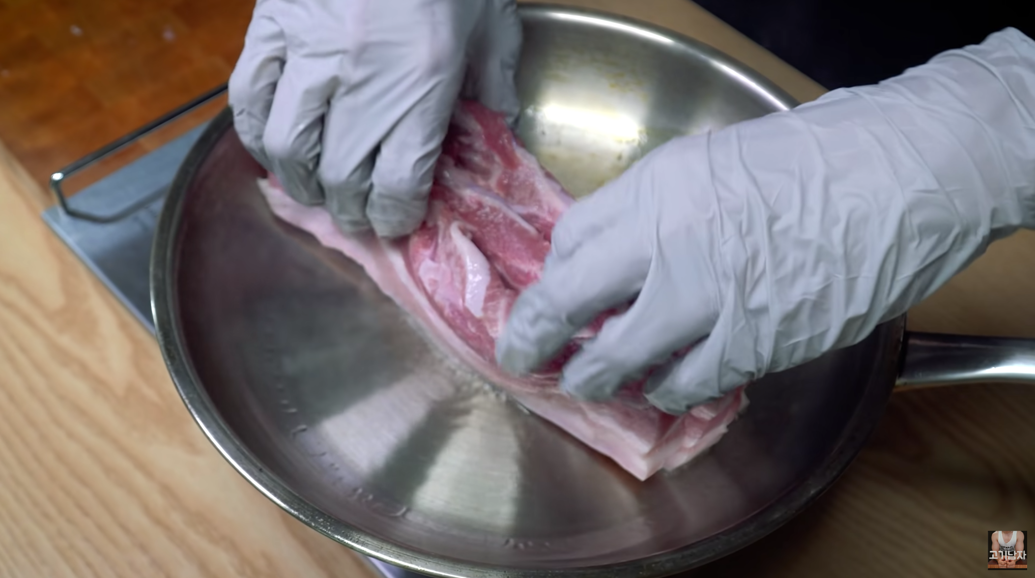 将生三层肉放入热锅中进行煎制，使用手套保护手部。