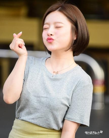 歌手ベンが、元気いっぱいで親指を立てている姿。カジュアルなグレーのTシャツを着用し、首に小さなペンダントをかけている。