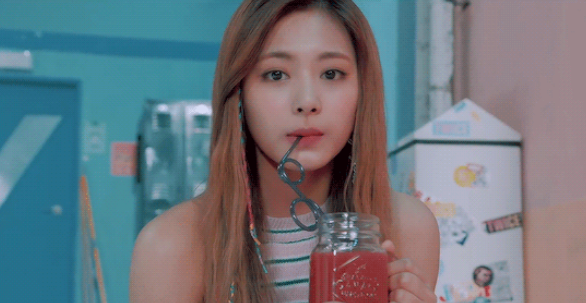 หญิงสาวถือแก้วน้ำสีแดงอยู่ในห้องที่มีผนังสีน้ำเงิน