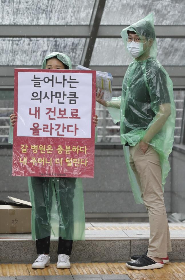 韩国医生在罢工期间手持抗议标语，上写增加医生工作量和减少薪资的指责。