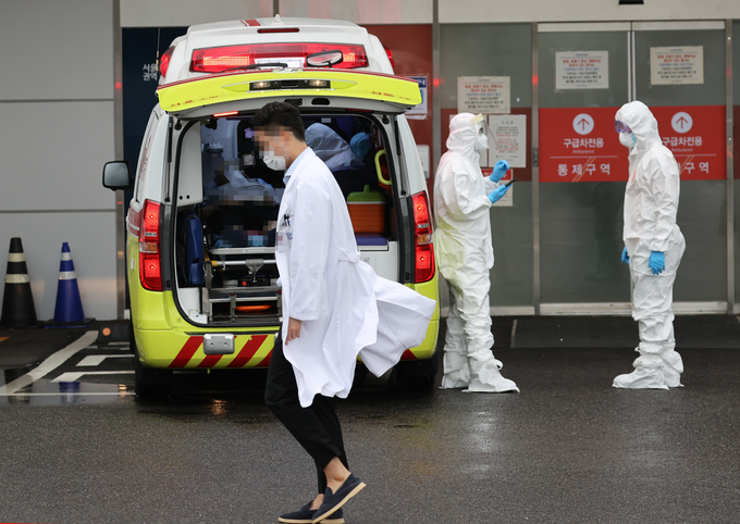 釜山医疗紧张期间，救护车在医院外等待急救，医护人员全副装备进行护理。