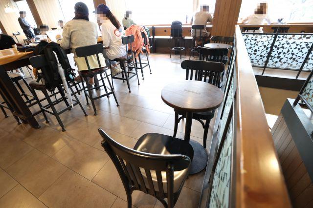 空いている座席で、スナックや飲み物でいっぱいのテーブルがあるソウル市内のカフェ。新型コロナウイルスの感染拡大による影響で無人となった様子を表すことで、人々が社会的距離を置いていることを示しています。