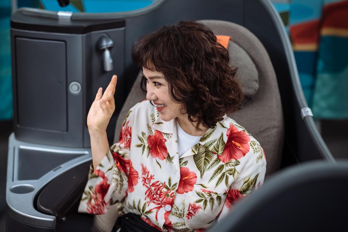 韩国电影《特务搞飞机》的片段中女主角坐在飞机座椅上，穿着有花卉图案的上衣。