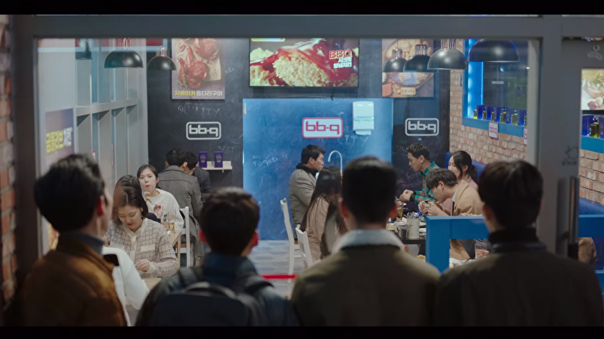 BBQ炸鸡连锁店内部热闹画面，韩剧《爱的迫降》中角色享受美食及友谊的聚餐地
