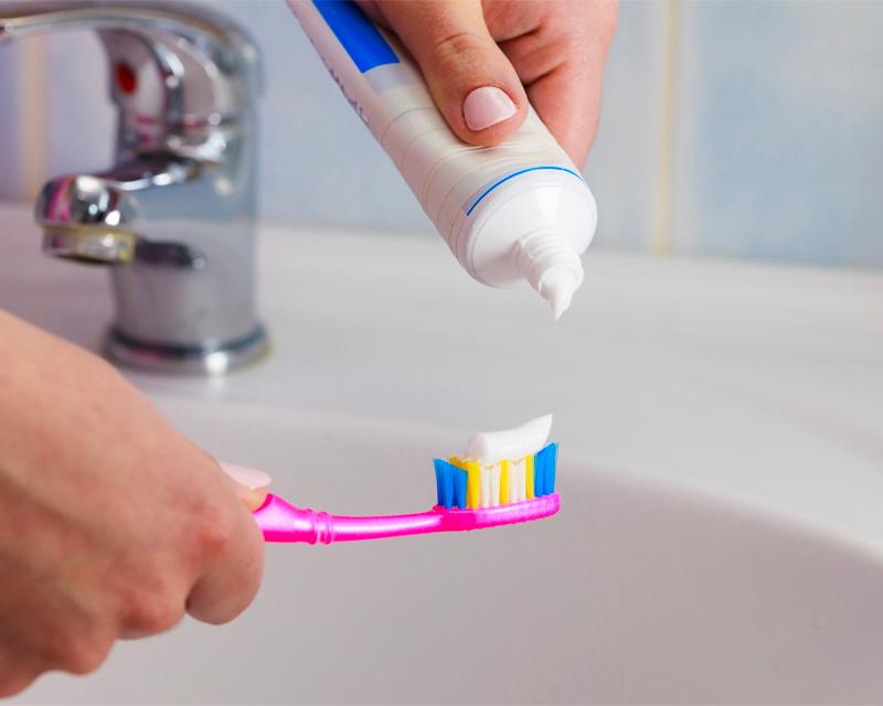 一個人在洗手間的水槽上正在牙刷上擠牙膏