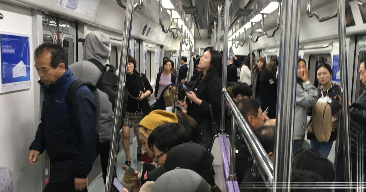 韓國地鐵車廂內部乘客狀況，描述繁忙時段的擠迫情況。