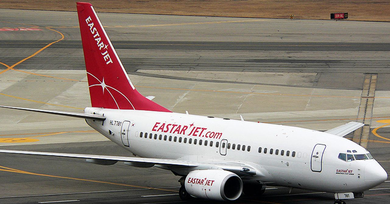 易斯達航空公司飛機停靠在跑道上的側視圖，展示了機尾上的品牌標誌和網站地址。