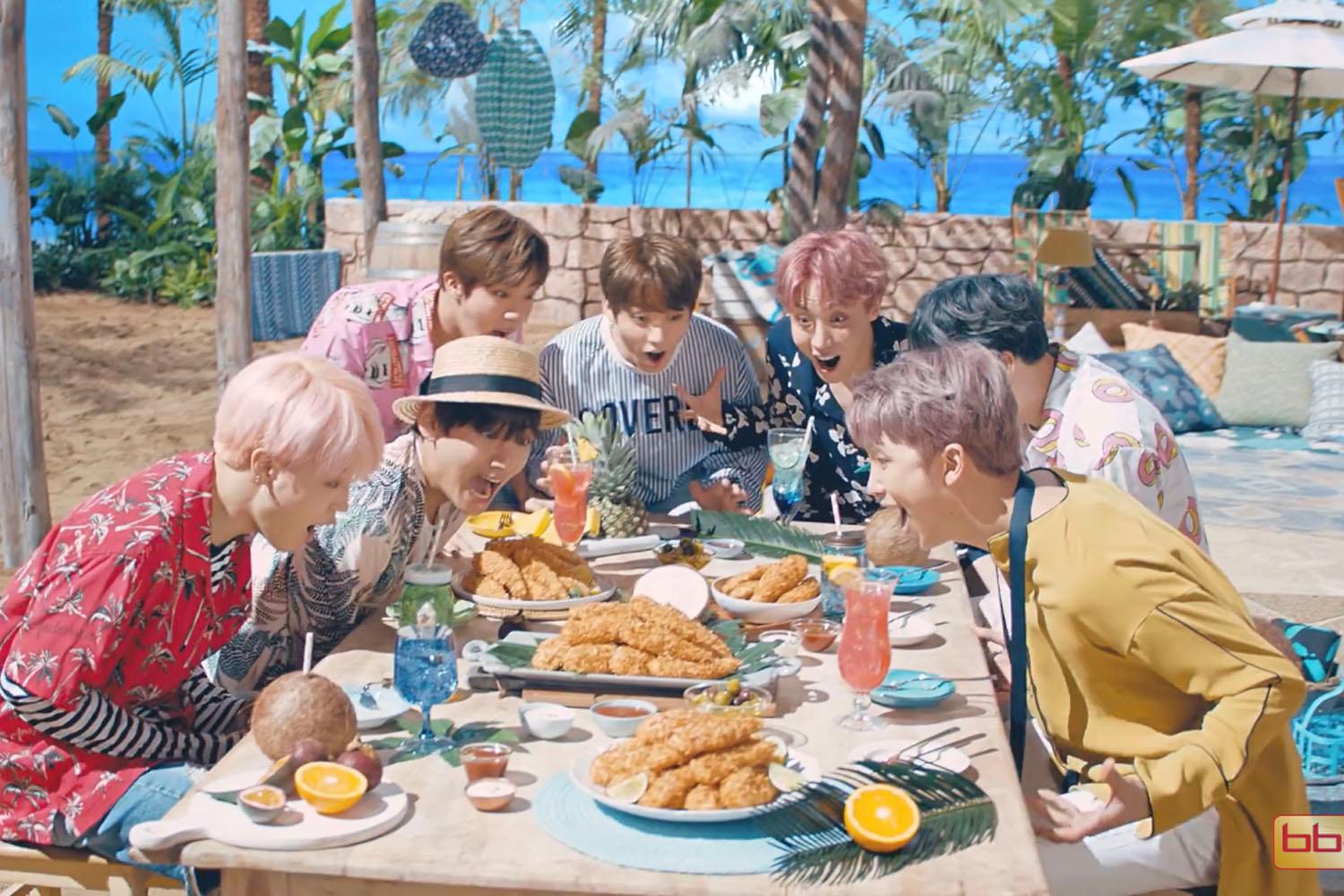 一羣朋友圍坐喺户外餐桌，面前擺滿咗炸雞同飲品。