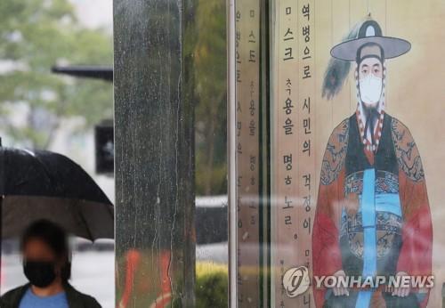 หน้าแรกของหนังสือพิมพ์ Yonhap เน้นสถานการณ์การระบาดของ COVID-19 กับภาพถ่ายป้ายบนท้องถนนที่เกาหลีใต้