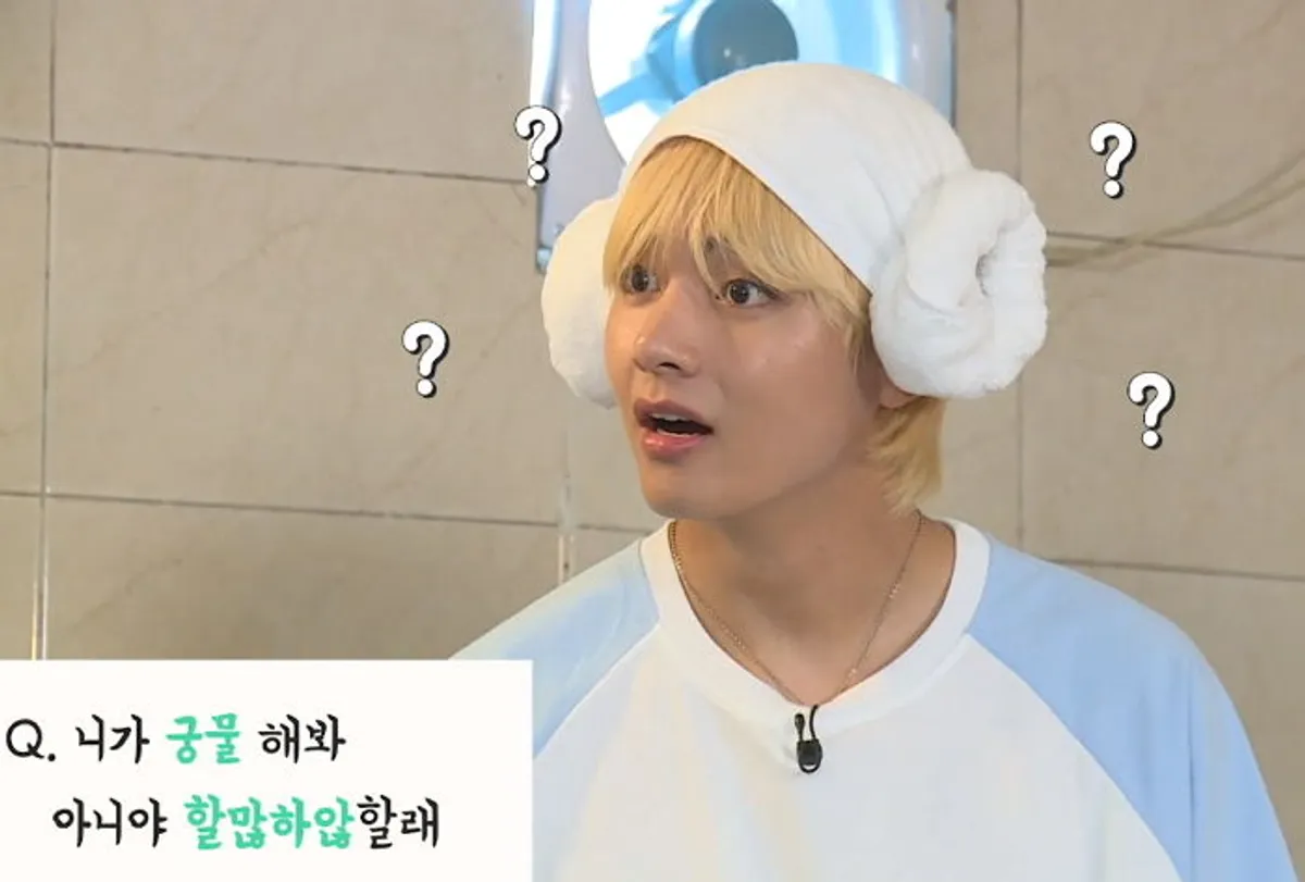 ผู้ชายแต่งตัวในห้องน้ำพร้อมผ้าพันหัวที่คล้ายกับหมวกหูแมวให้ความรู้สึกมุ่งมั่นในสภาพแวดล้อมที่เป็นกันเอง ถามเกาหลีว่าถ้ามีคำถามอะไรให้ถามเลย เป็นภาพจากรายการโทรทัศน์ที่แสดงให้เห็นถึงบรรยากาศที่สนุกสนานและผ่อนคลายในการสนทนาเกี่ยวกับภาษาและวัฒนธรรมเกาหลี คำถามมีอักษรเกาหลีในภาพ ซึ่งสื่อถึงการเรียนรู้อย่างเบาๆ สบายๆ เกี่ยวกับวัฒนธรรมและภาษาที่นิยมใช้ในเกาหลี