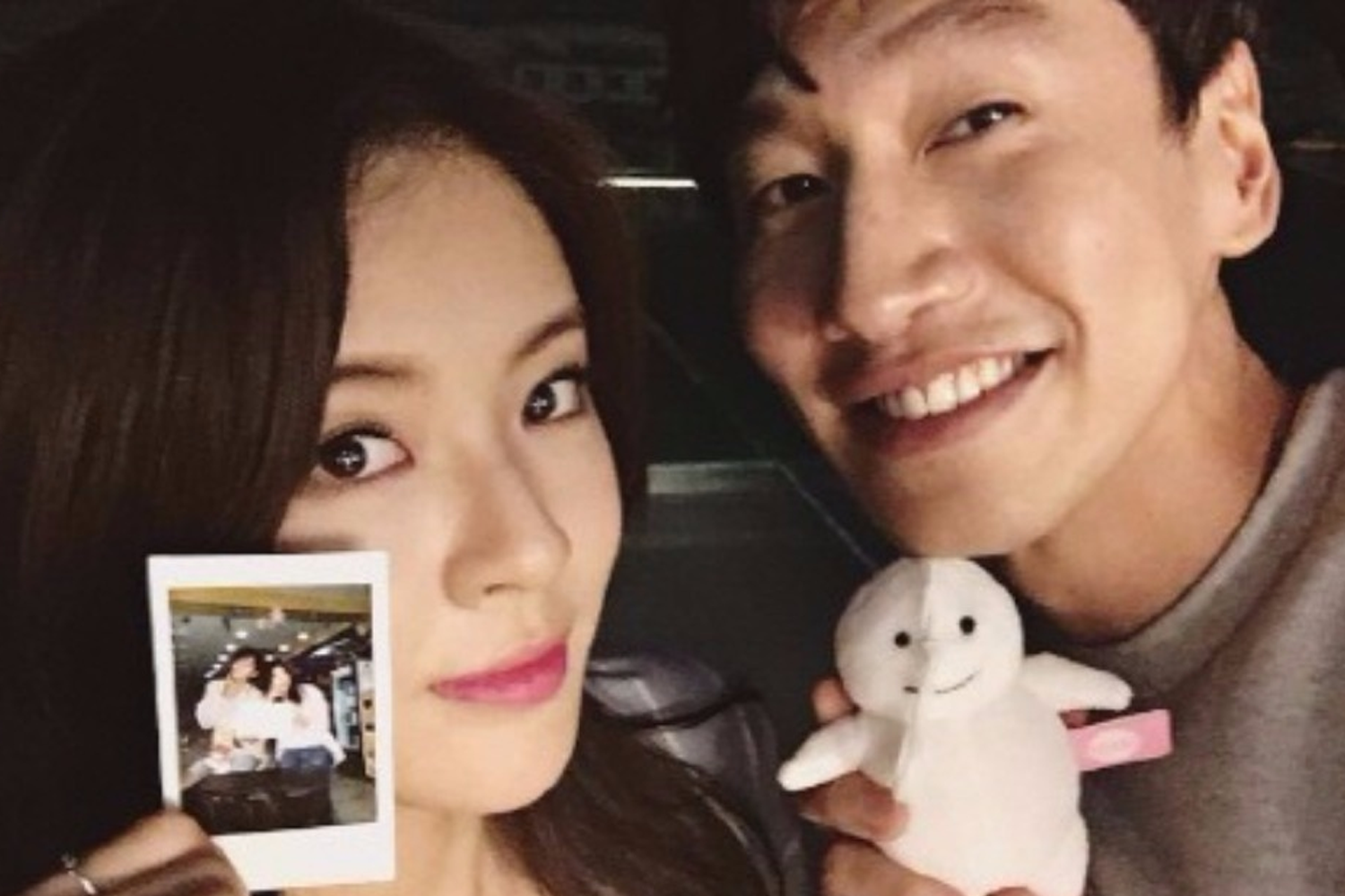 一對情侶面對面微笑，男生手中拿著白色微笑玩偶，顯示了愉快和親密的時刻。