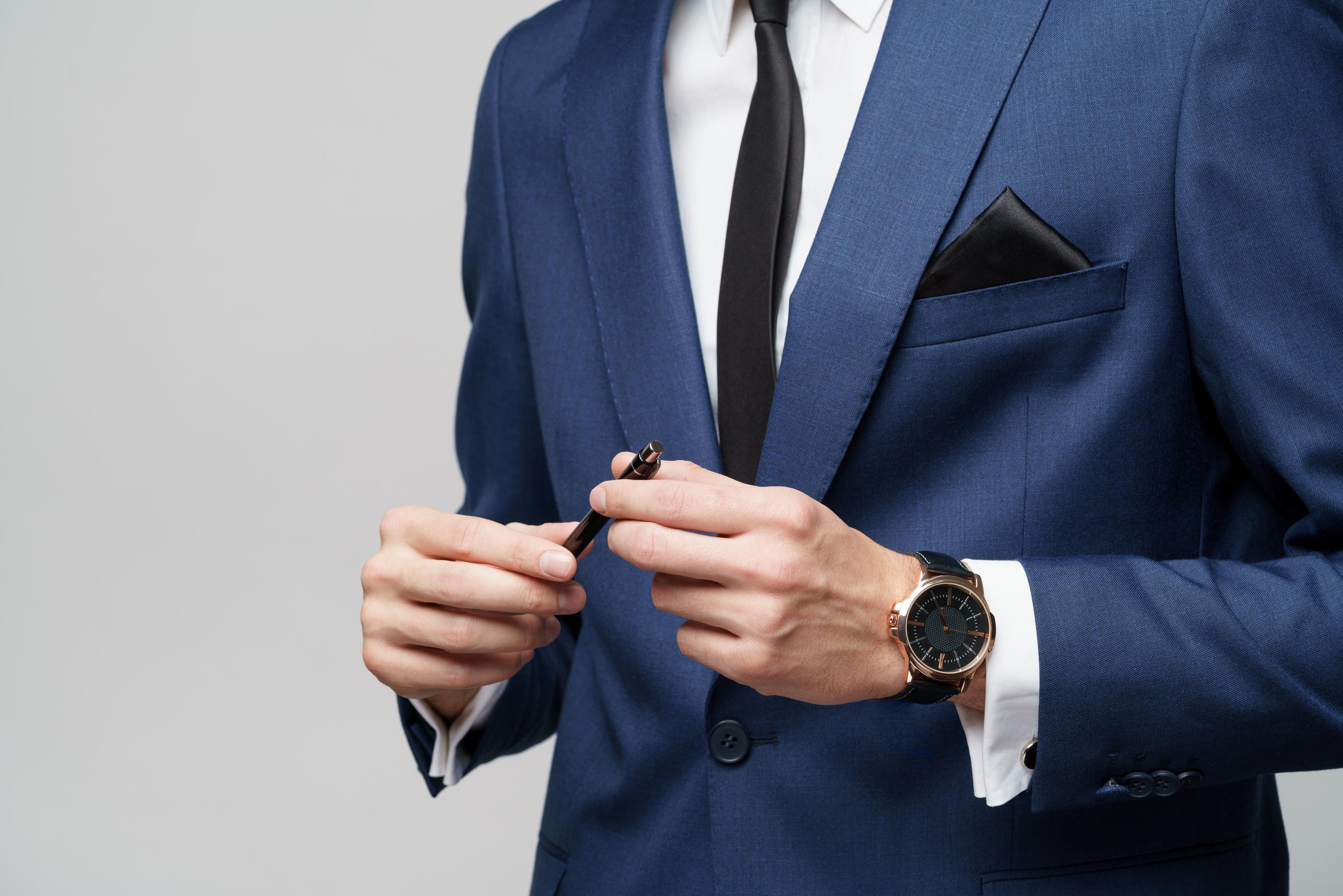 穿著藍色正裝的男人向觀眾展示他的西裝配件，象徵著專業和自信。