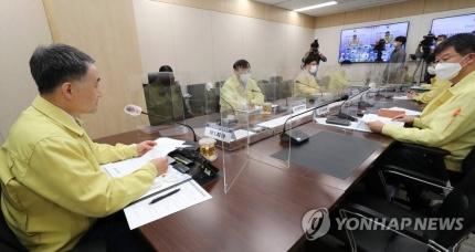 韓国政府の会議室で、ビニール仕切りを設置してソーシャルディスタンスを確保する形で行われている中央災難安全対策本部の会議の様子。出席者たちは室内でマスクを着用し、新型コロナウイルス防疫対策の遵守を示している。