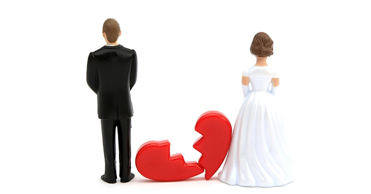 一對新郎和新娘的公仔背對背，與一個破裂的紅色心形，象徵破裂婚姻的視覺概念。