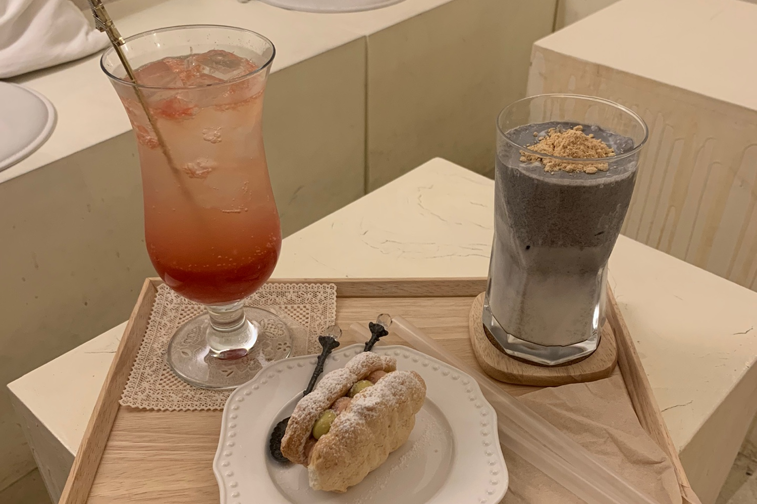 托盤上的裝飾飲品和甜點，包括西柚Ade和黑芝麻拿鐵，展示了咖啡廳的精緻美食和獨特搭配。