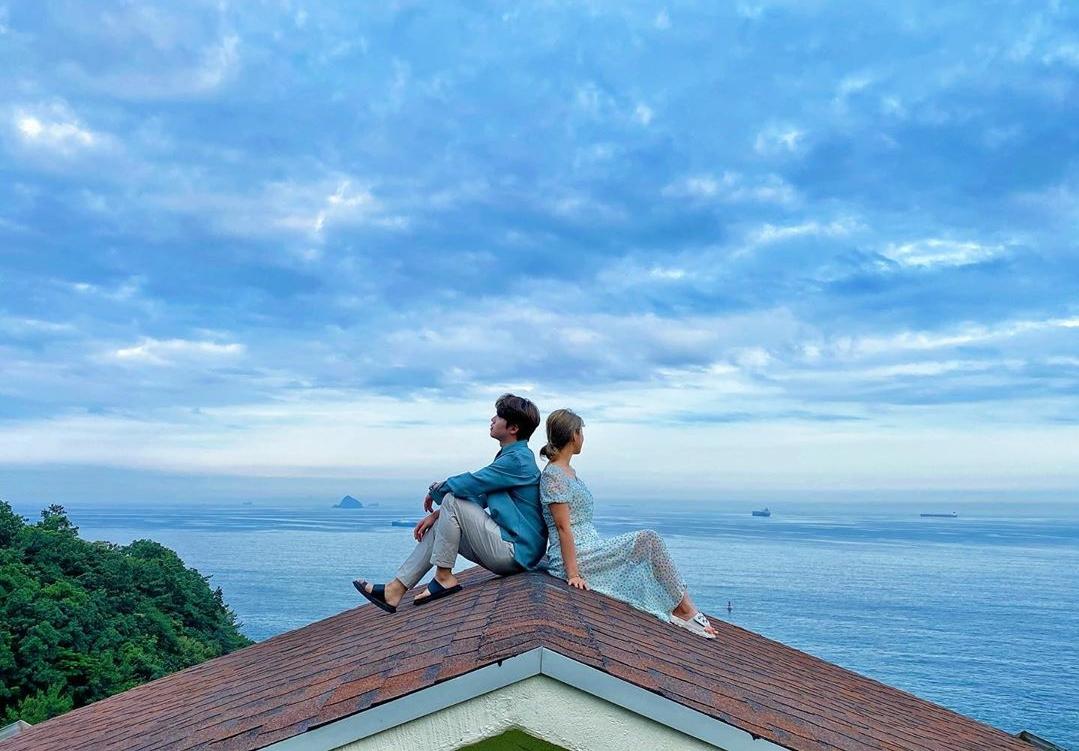ein Paar, das auf dem Dach posiert und auf das Meer am Namhae Maru & Ara Pension blickt
