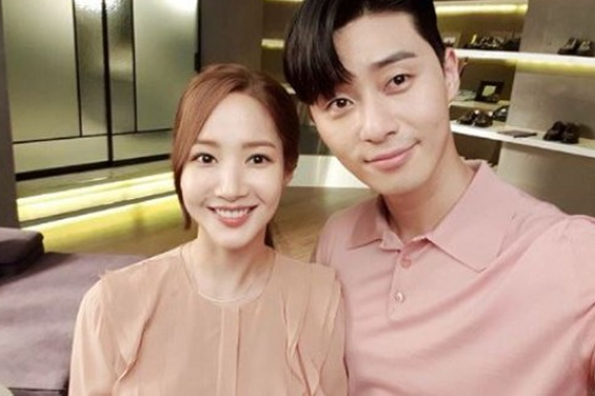 著粉紅色襯衫的情侶在優雅的室內場景中，他們的相識源於改編自2013年的人氣網漫《金秘書為何那樣》，他們的搭配引發無數網友的猜測和討論。