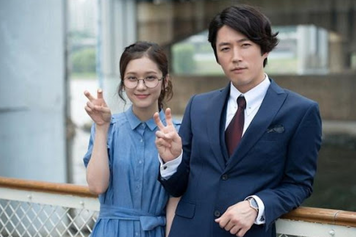 站在户外，身著西裝與藍色連衣裙的情侶用手勢比劃著勝利的姿勢。該情侶主演《命中註定我愛你》，其浪漫愛情故事源自於另一部受歡迎的台劇。