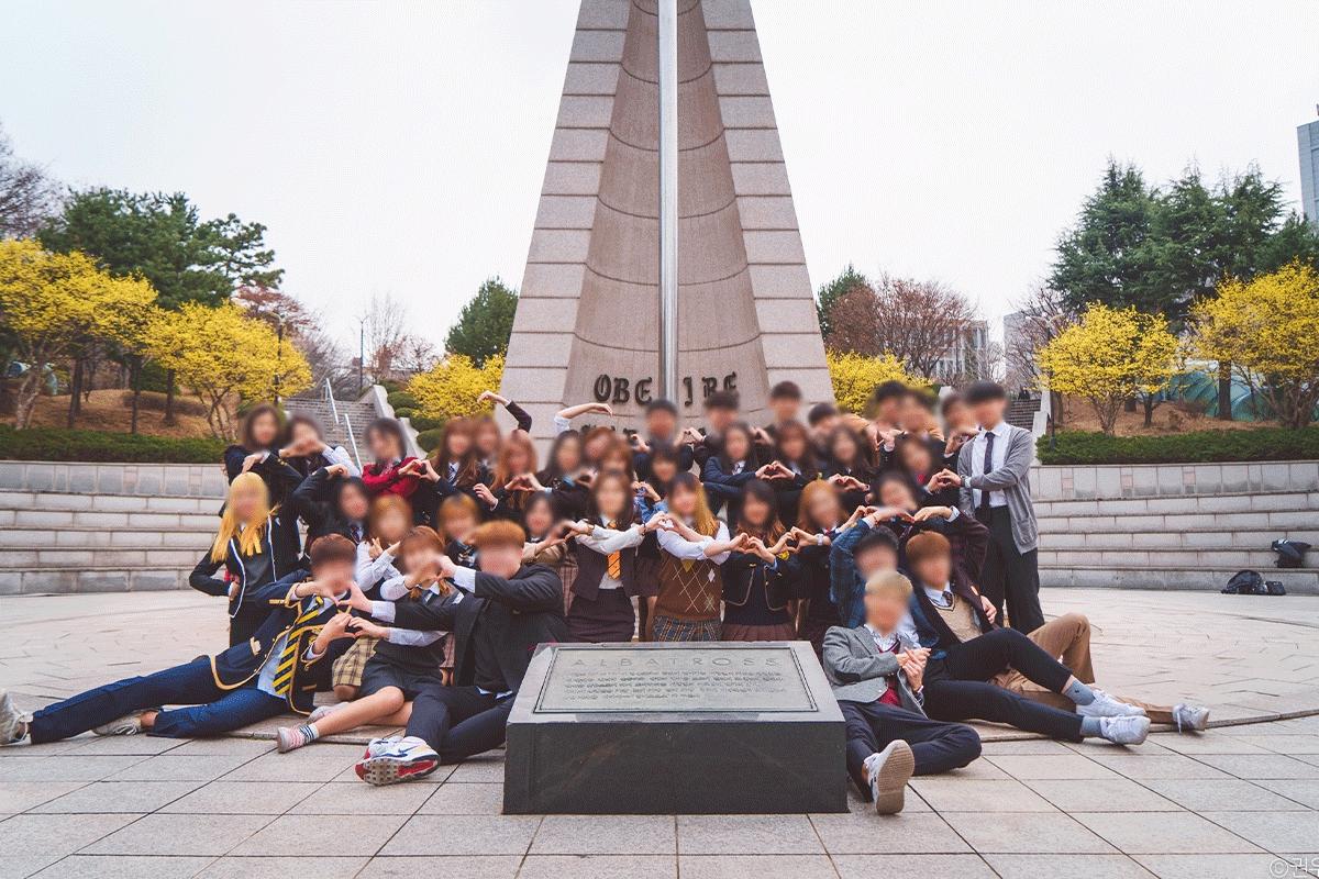 Korean college students dressed in high school uniforms taking a group photo during an April Fool's Day event on campus, capturing the playful tradition in universities.