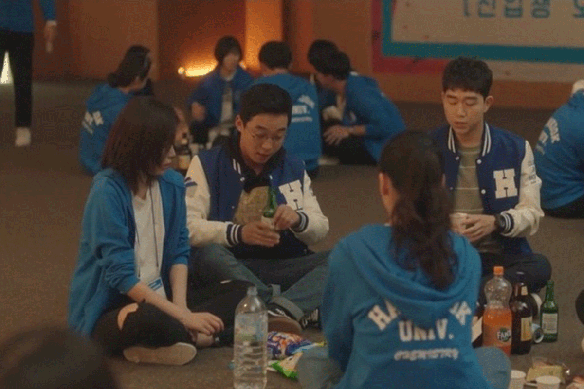 Sinh viên đại học Hàn Quốc ngồi thành nhóm trong một sự kiện, trên bàn có các chai đồ uống.