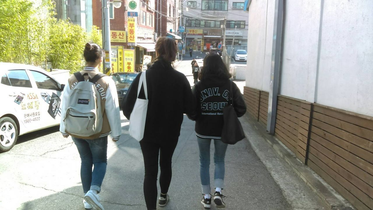 在校園中，一羣穿著校服的韓國大學生由後面走向教學樓