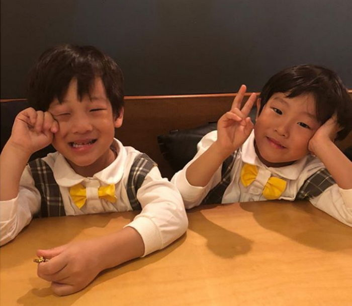 兩位穿著格子背心和黃色領結的男孩坐在餐桌前，這是一幅甜美的童年瞬間。