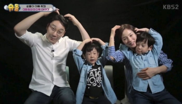 一家人在電視節目上做出可愛的心形姿勢，展示著和諧的家庭氣氛。