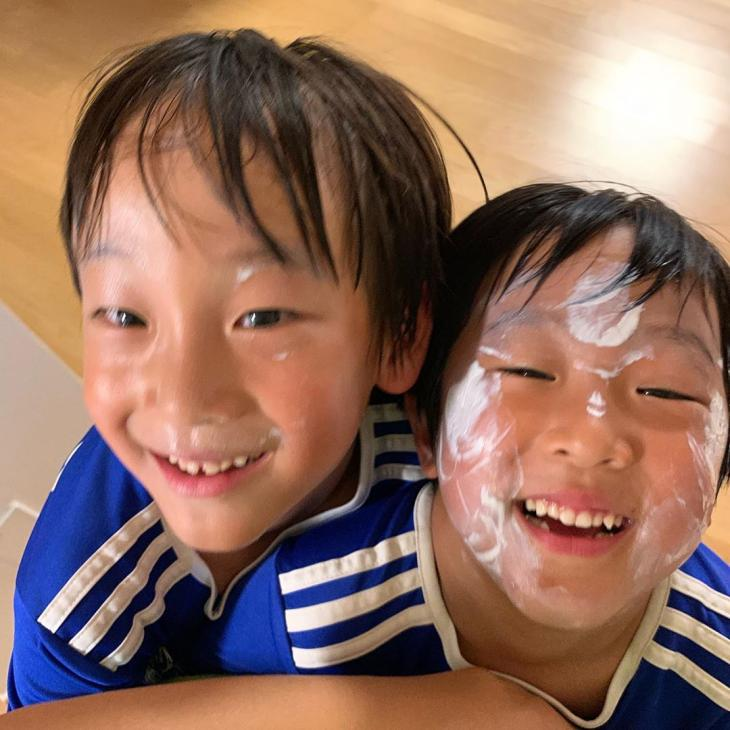 兩位身穿藍色運動服的男孩在家中擺出緊密的姿勢，伴隨著家庭的温馨氛圍。