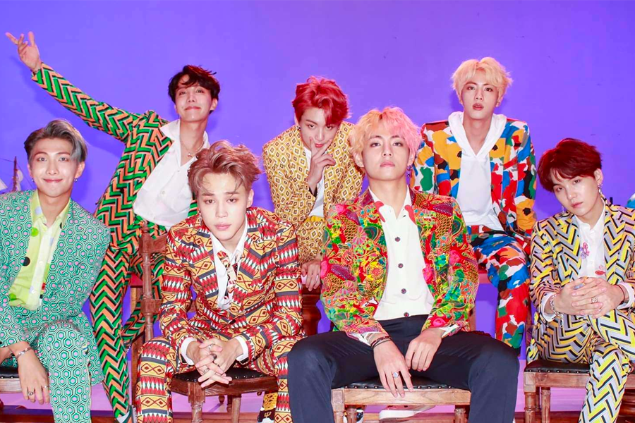 BTS團體成員穿著華麗的民族風格服裝，以紫色背景展示韓國K-pop的流行標誌和視覺效果。