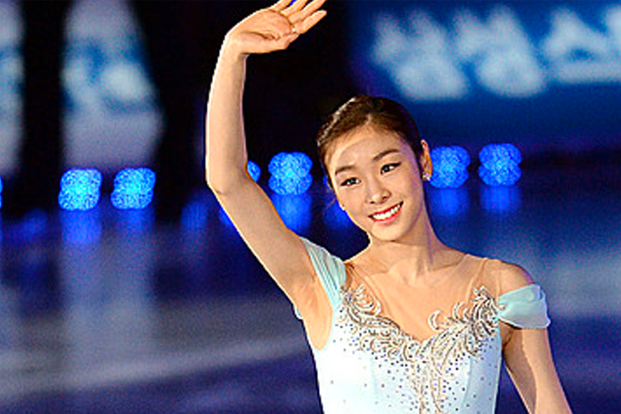 金妍兒在冰場上穿著藍色花式滑冰服裝向觀眾揮手，展示她的運動天分和韓國體育成就。