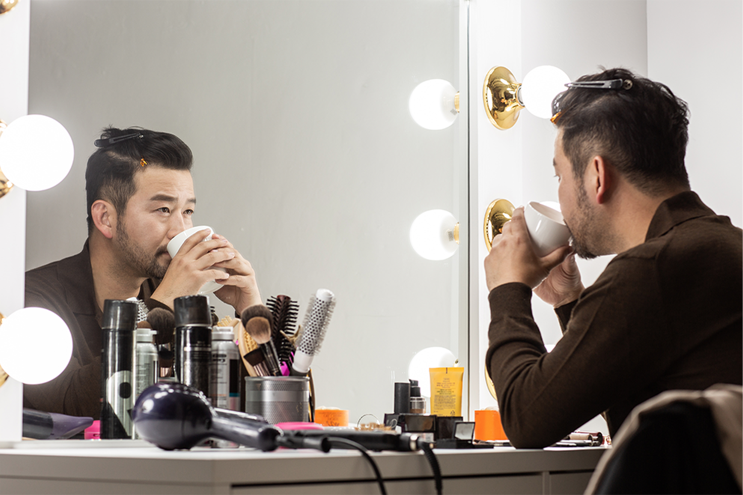 化妝桌上放置各種化妝品和髮型工具，鏡子反射出這些項目，是化妝或造型的場景。