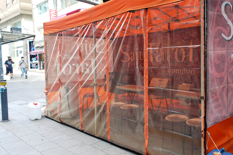 在韓國街頭可見的塔羅牌占卜小攤位，透明橘色布簾包圍的攤位，內部有座椅和桌子。