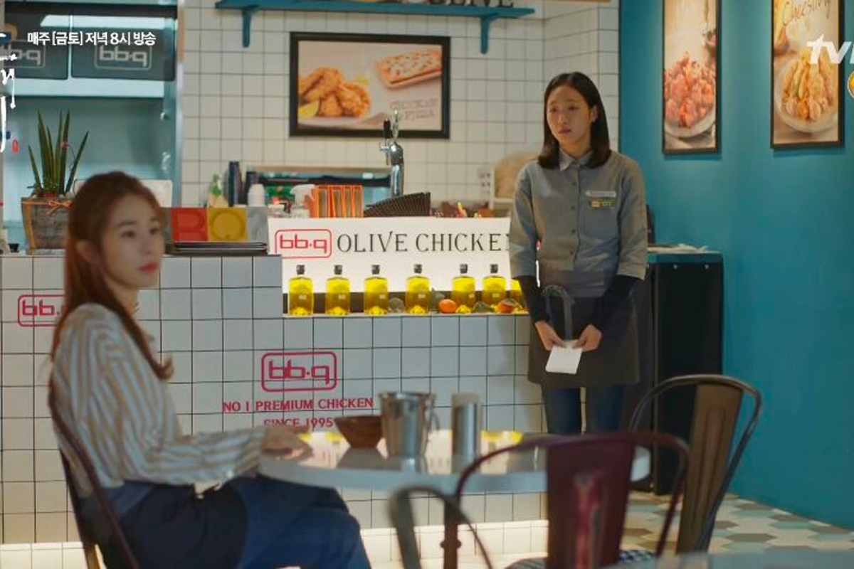 韓國BBQ Olive Chicken咖啡廳內,服務員與顧客正在交流,牆壁上展示著炸雞的海報。