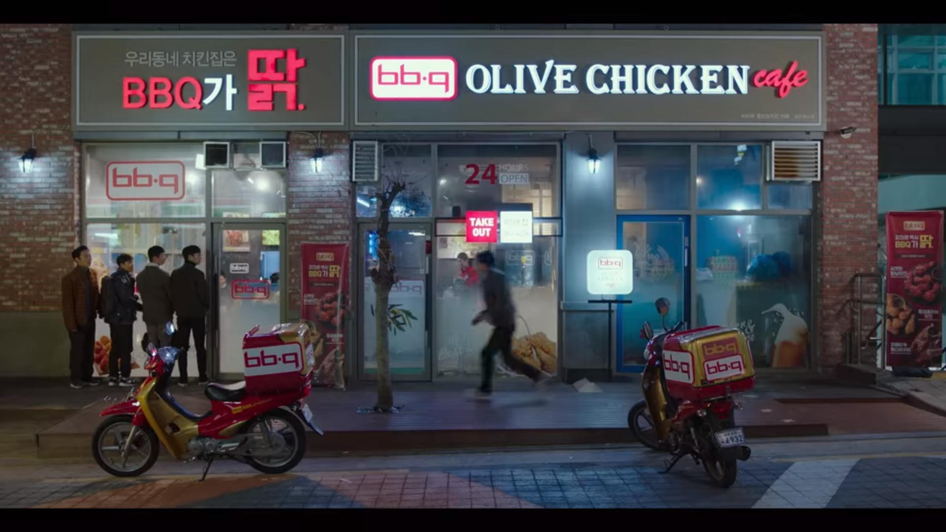 ด้านหน้าร้านไก่ทอดบีบีคิวส์ โอลีฟ ชิคเก้น คาเฟ่ พร้อมกล่องเดลิเวอรี่บนมอเตอร์ไซค์จอดอยู่ข้างหน้า