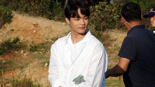 严肃的拍摄现场，金秀午穿着白色上衣，与剧组成员一起投入剧烈的拍摄场景。