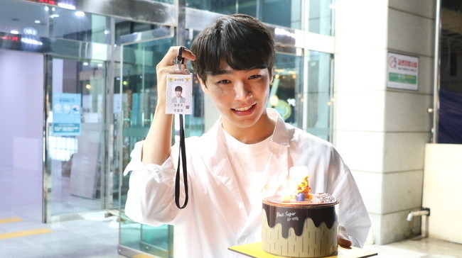 演员金秀午在《恶之花》剧组中扮演忙内刑警，手持生日蛋糕，展现出创意节目幕后庆祝场景。