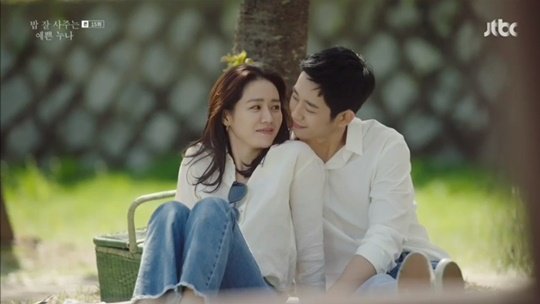 คู่รักนั่งใต้ต้นไม้ในสวนสาธารณะพิงกันอย่างสนิทสนมในช่วงเวลากลางวัน ที่ประเทศเกาหลี