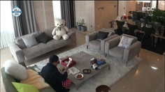 リビングルームのソファの上にゴロゴロとしたテディベアが置かれて、床に座り食事をする様子を映した韓国の家庭内風景。